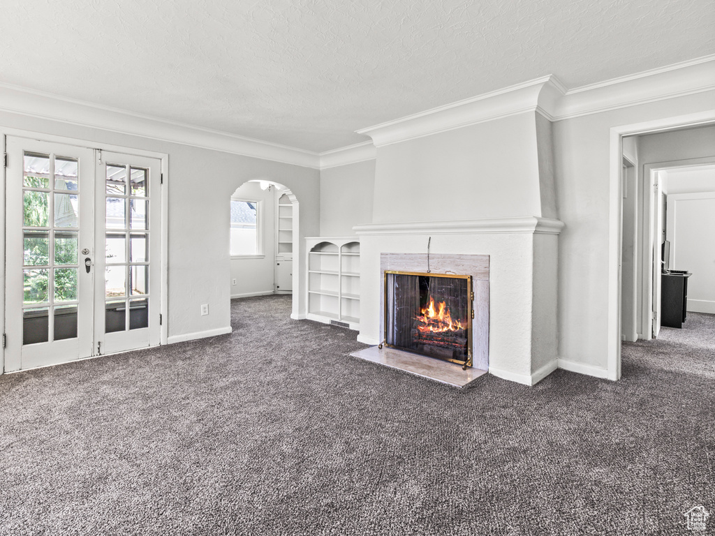 Unfurnished living room with crown molding, french doors, and a healthy amount of sunlight