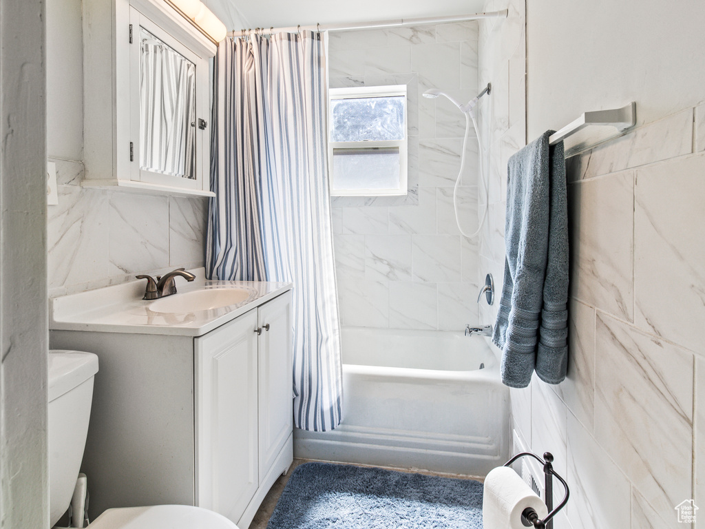 Full bathroom featuring vanity, tile walls, toilet, and shower / bath combination with curtain