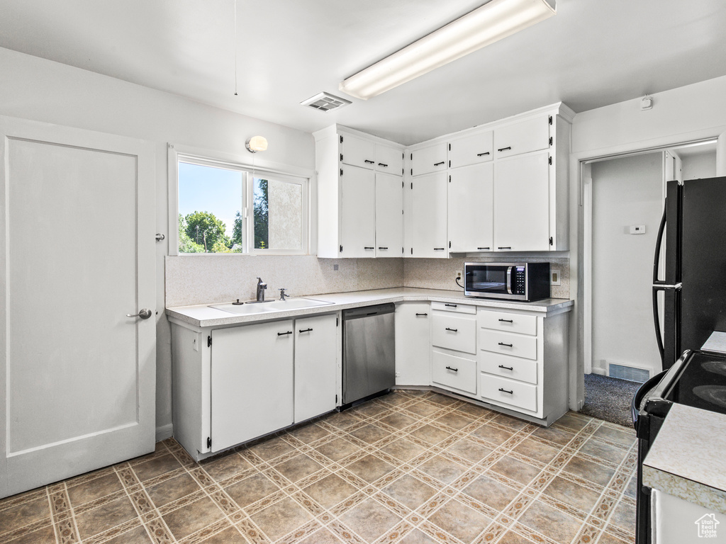 Kitchen with decorative backsplash, stainless steel appliances, and white cabinets