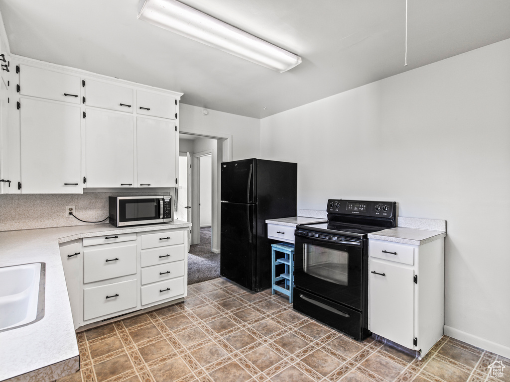 Kitchen featuring white cabinets, black appliances, tile patterned flooring, and tasteful backsplash