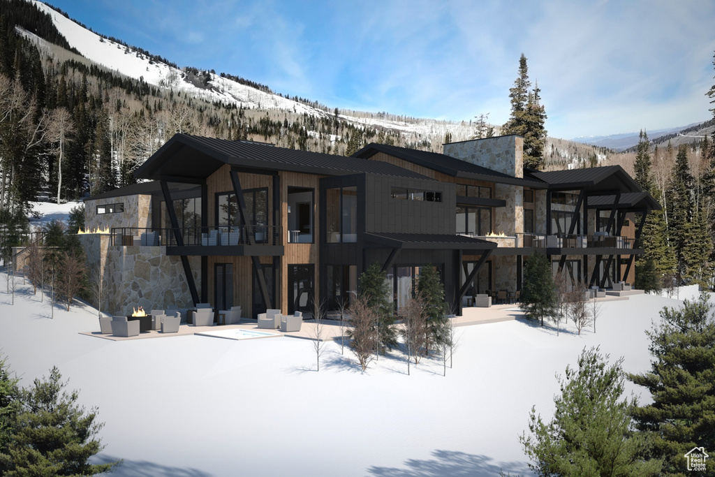 Snow covered house featuring a patio and a balcony