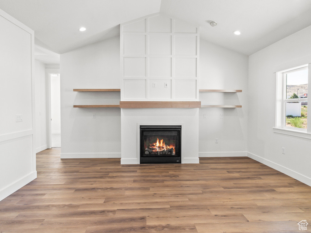 Unfurnished living room with lofted ceiling and hardwood / wood-style floors