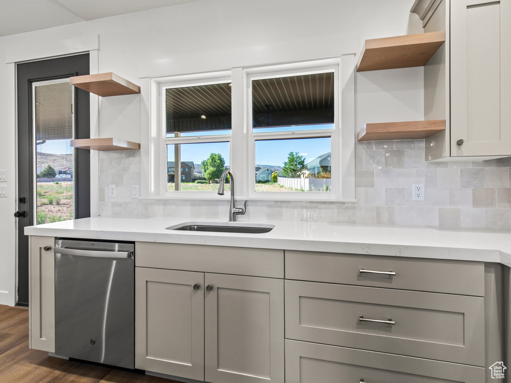 Kitchen featuring sink, gray cabinets, backsplash, stainless steel dishwasher, and dark hardwood / wood-style floors