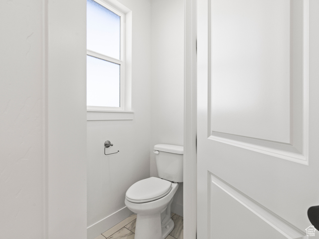 Bathroom featuring toilet, tile patterned flooring, and plenty of natural light