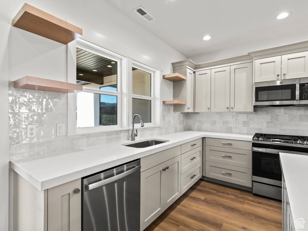 Kitchen with sink, appliances with stainless steel finishes, dark hardwood / wood-style floors, and tasteful backsplash