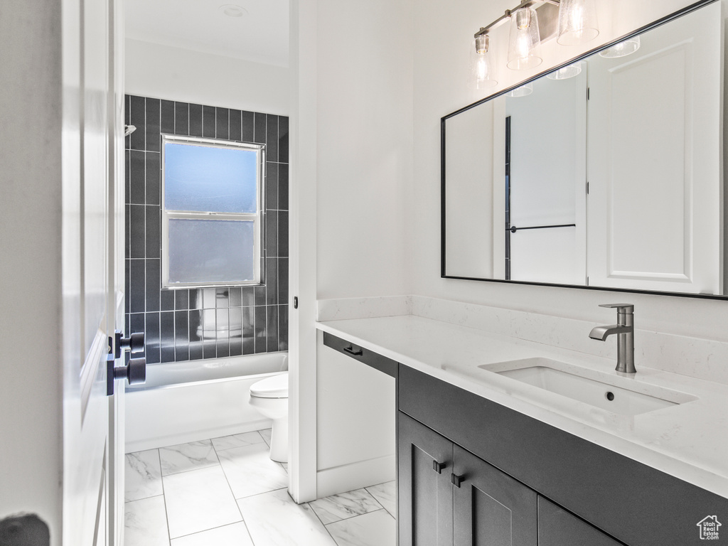 Full bathroom with tiled shower / bath combo, tile patterned floors, toilet, and vanity