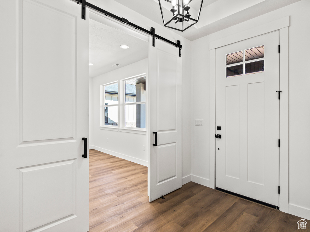 Foyer with an inviting chandelier, wood-type flooring, and a barn door