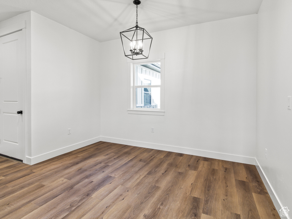 Unfurnished room featuring hardwood / wood-style flooring and a chandelier