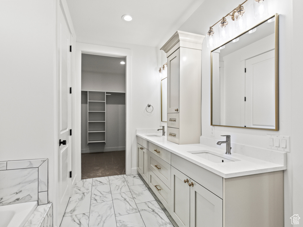 Bathroom with a tub to relax in, tile patterned flooring, and double vanity