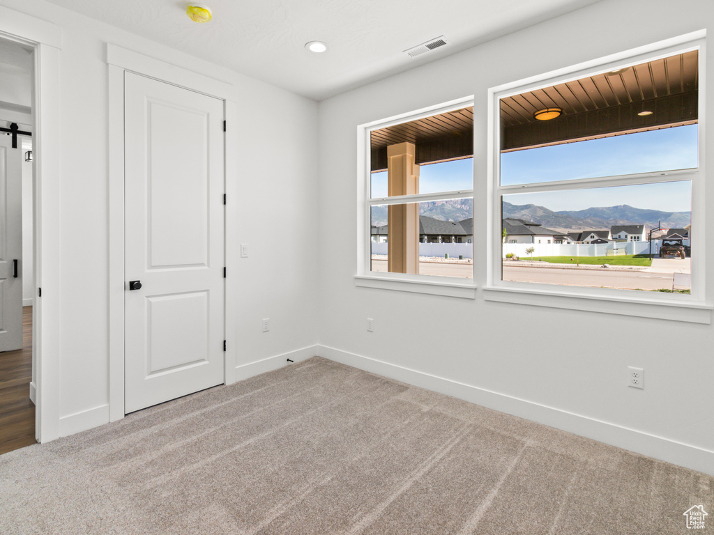 Unfurnished bedroom featuring a mountain view, a barn door, and carpet flooring