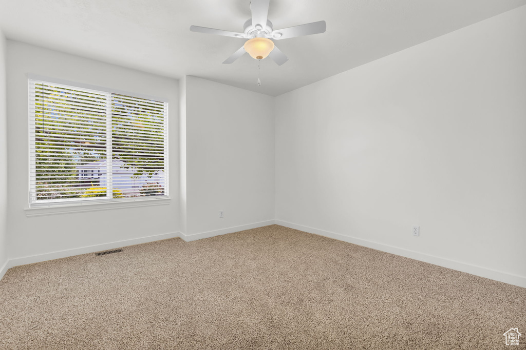 Carpeted spare room with ceiling fan