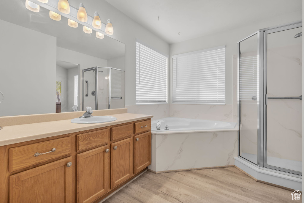 Bathroom featuring hardwood / wood-style flooring, separate shower and tub, a healthy amount of sunlight, and vanity