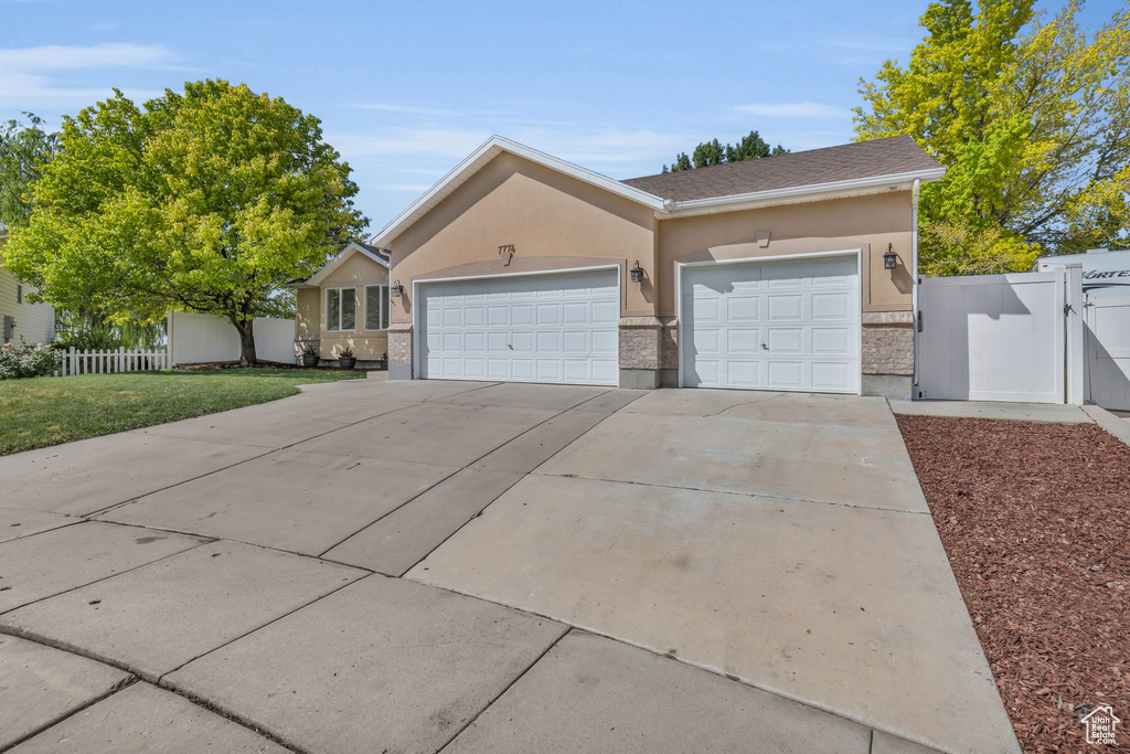 Single story home with a garage and a front lawn