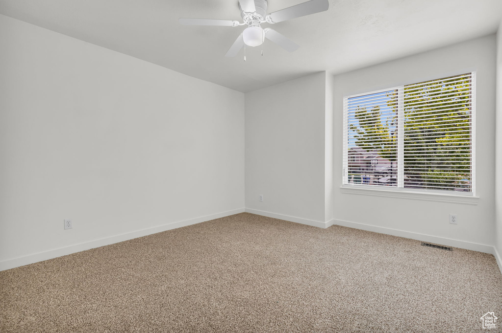 Unfurnished room with ceiling fan, carpet floors, and plenty of natural light