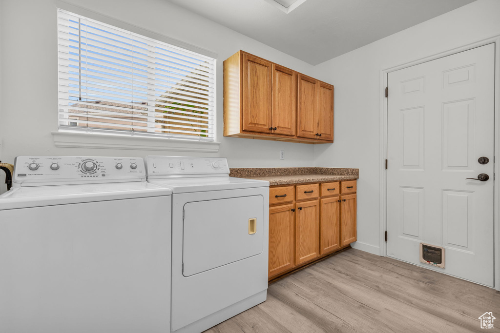 Laundry room with separate washer and dryer, light hardwood / wood-style flooring, and cabinets