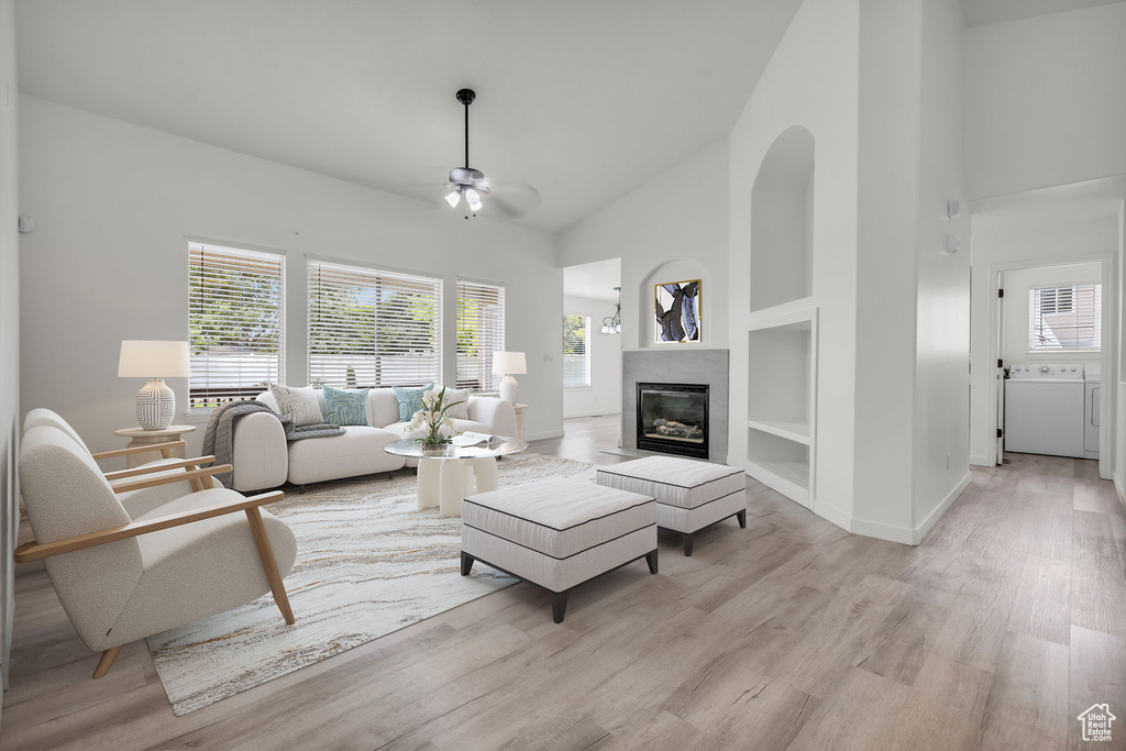 Living room featuring light hardwood / wood-style floors, built in features, ceiling fan, and high vaulted ceiling