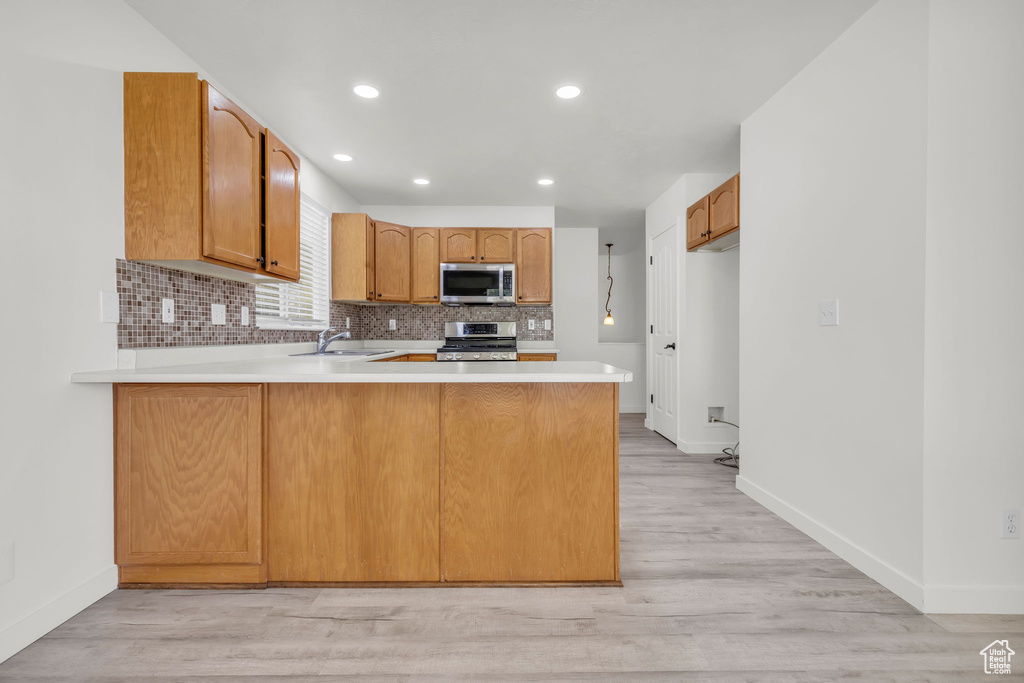 Kitchen featuring appliances with stainless steel finishes, light wood-type flooring, and kitchen peninsula