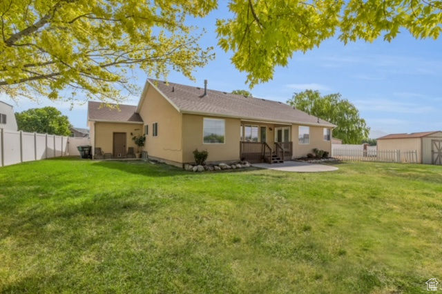 Rear view of house with a storage unit and a lawn