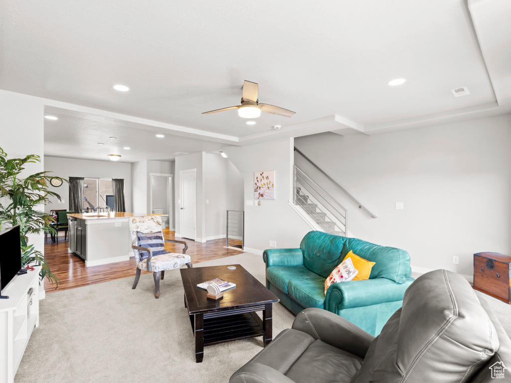 Living room with ceiling fan and light hardwood / wood-style flooring