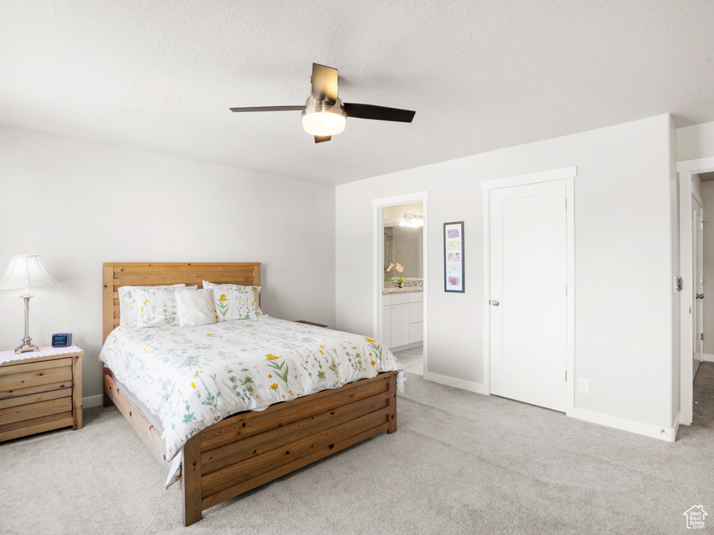 Carpeted bedroom with ensuite bath and ceiling fan