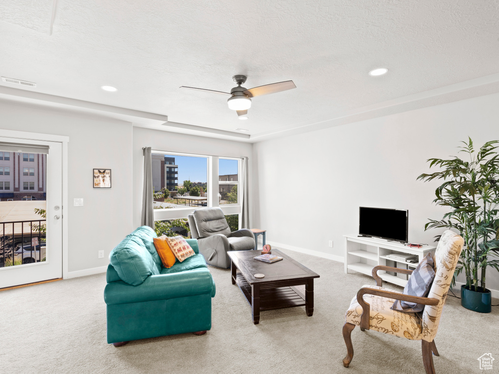 Living room featuring a textured ceiling, ceiling fan, and carpet flooring