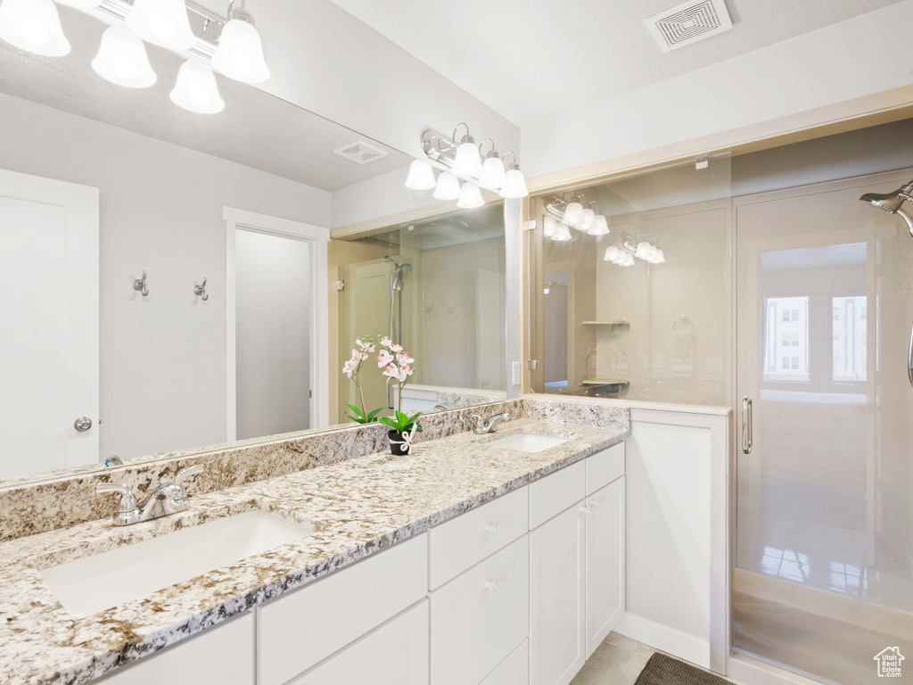 Bathroom featuring tile patterned flooring, double sink vanity, and an enclosed shower