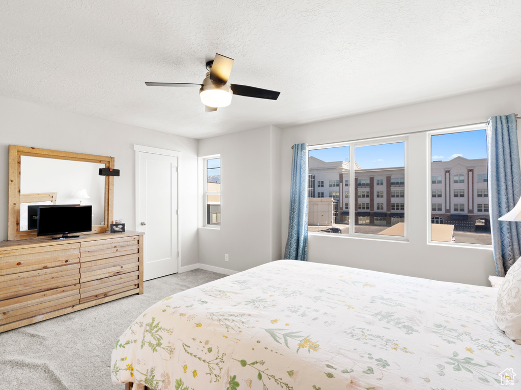 Bedroom with a textured ceiling, ceiling fan, and light colored carpet