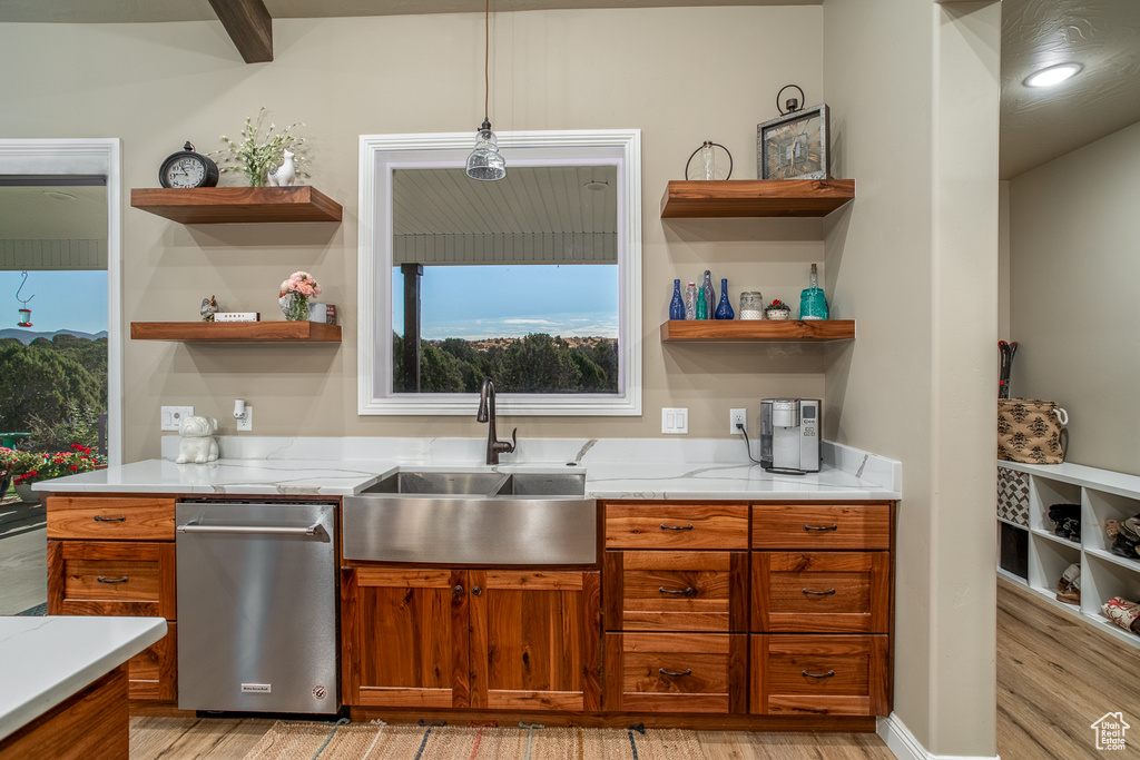 Kitchen with light stone counters, pendant lighting, light hardwood / wood-style flooring, and sink