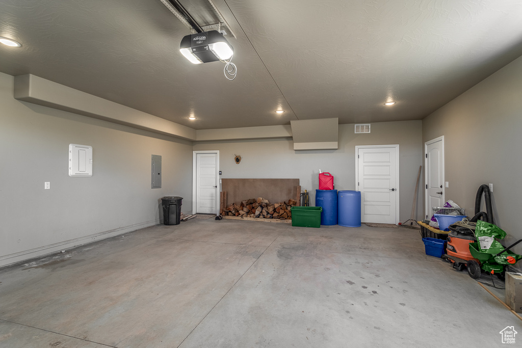 Garage featuring a garage door opener and electric panel