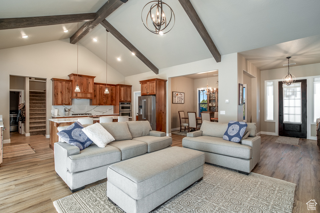 Living room featuring light wood-type flooring, beam ceiling, a chandelier, and high vaulted ceiling