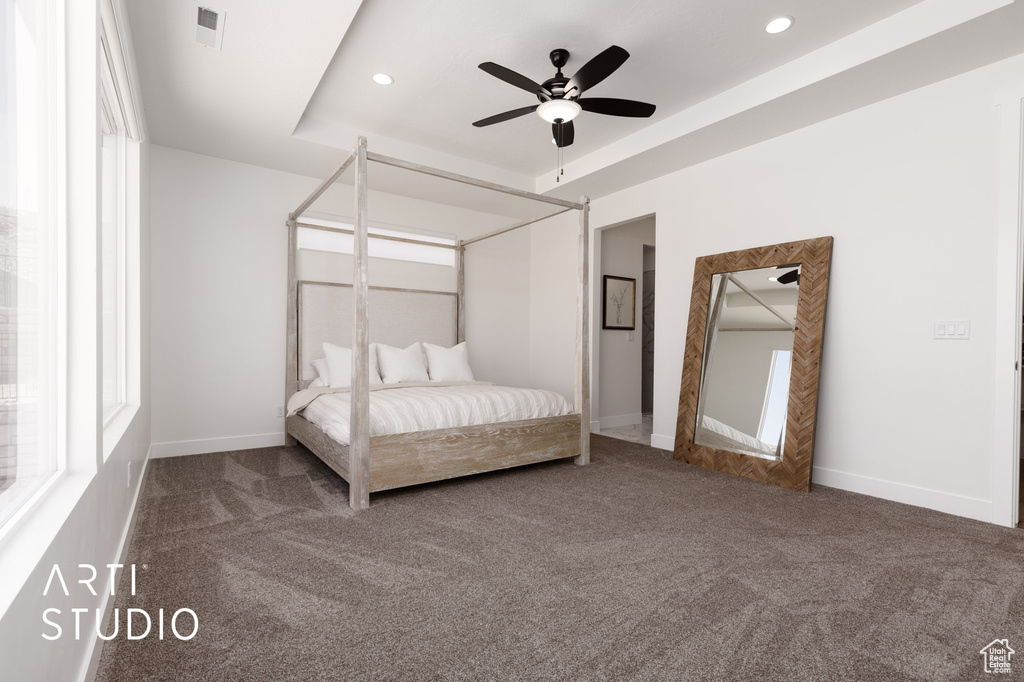 Unfurnished bedroom with dark carpet, ceiling fan, and a raised ceiling