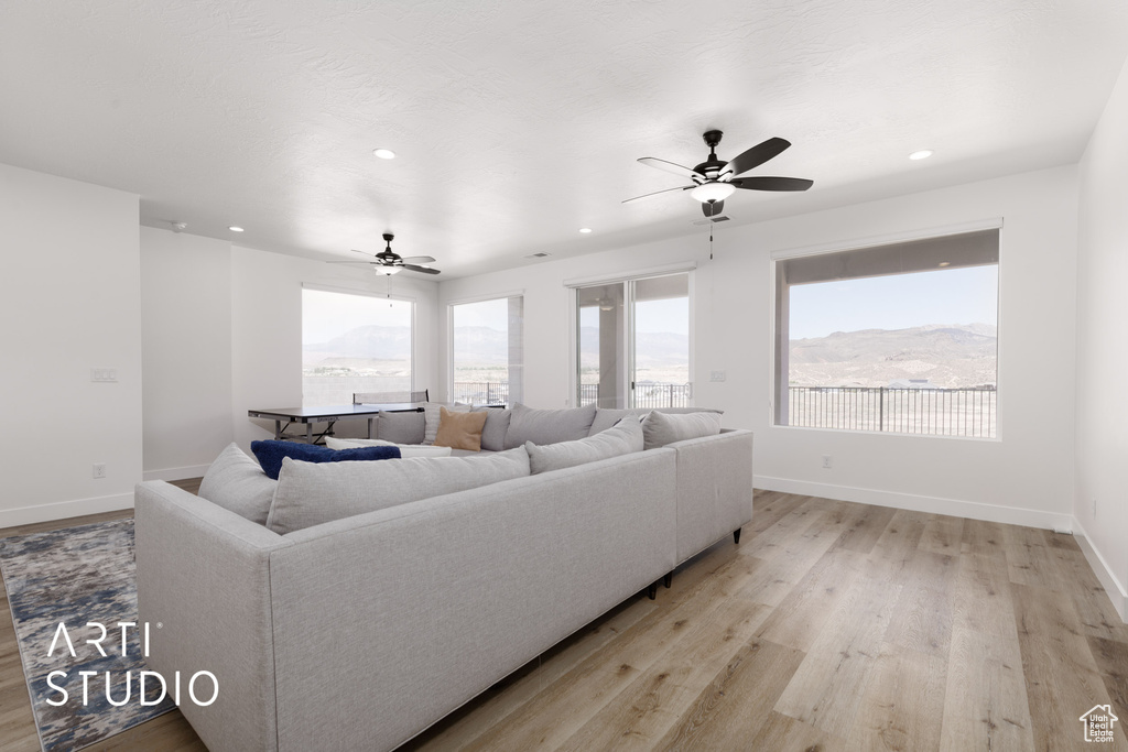 Living room featuring light wood-type flooring, ceiling fan, and a mountain view