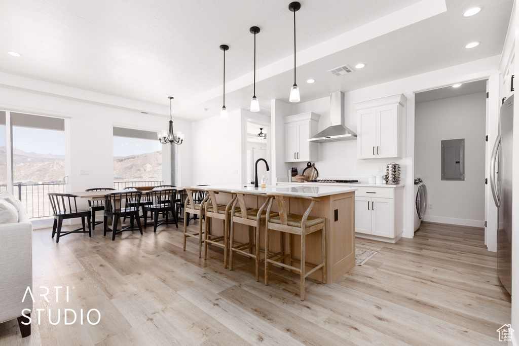 Kitchen featuring light hardwood / wood-style flooring, white cabinets, and wall chimney exhaust hood