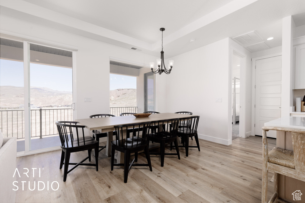 Dining space with light hardwood / wood-style floors, an inviting chandelier, and a mountain view