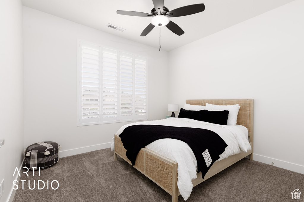 Carpeted bedroom featuring multiple windows and ceiling fan