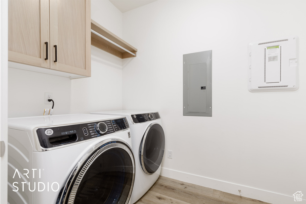 Laundry room with independent washer and dryer, light hardwood / wood-style floors, electric panel, and cabinets