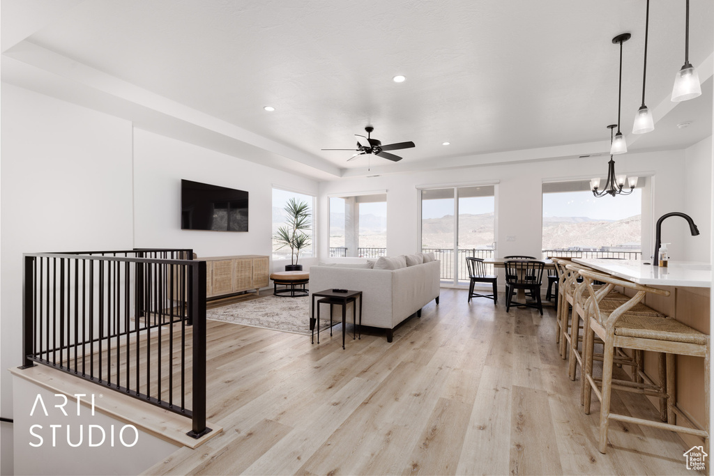 Living room with light hardwood / wood-style floors, ceiling fan with notable chandelier, and a mountain view