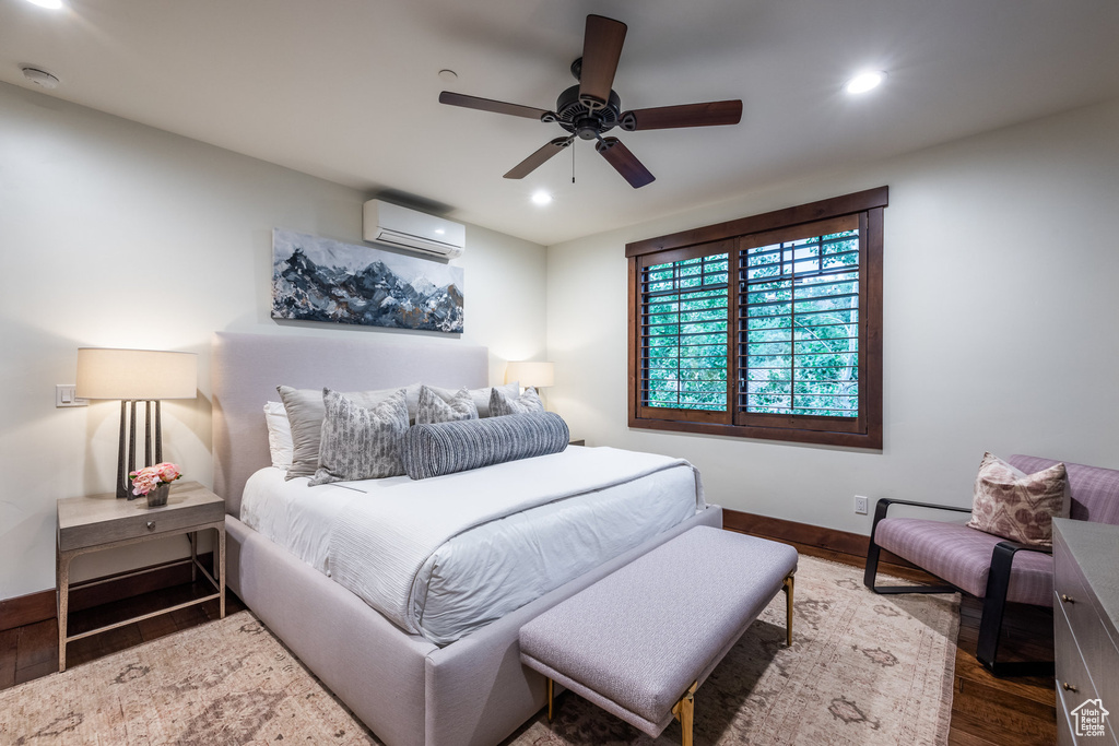 Bedroom featuring a wall unit AC, ceiling fan, and dark wood-type flooring