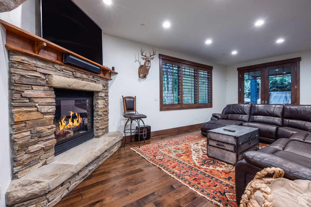 Living room with a stone fireplace, dark hardwood / wood-style floors, and french doors