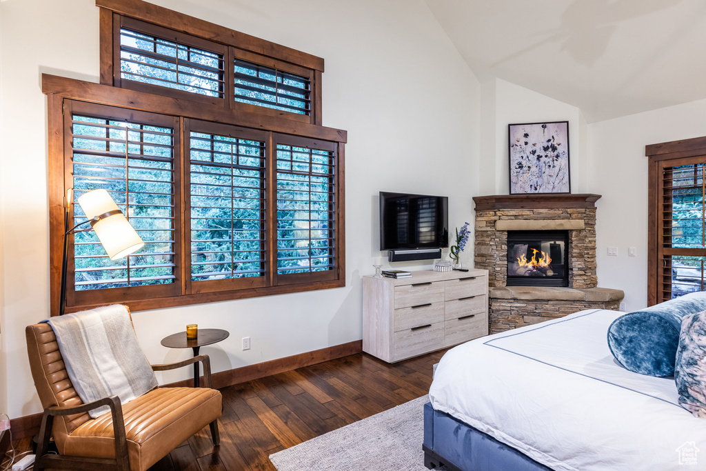 Bedroom featuring vaulted ceiling, a stone fireplace, and dark hardwood / wood-style floors