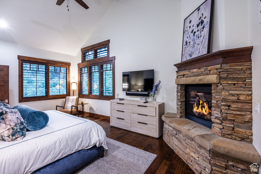 Bedroom with a stone fireplace, vaulted ceiling, dark hardwood / wood-style flooring, and ceiling fan