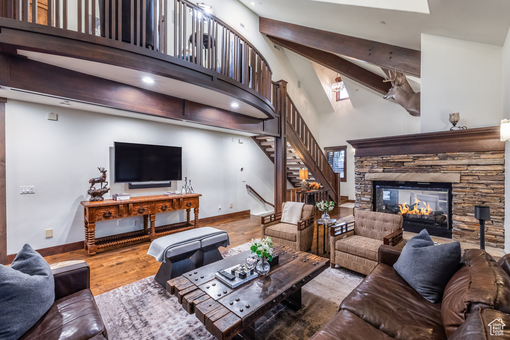 Living room with beamed ceiling, a fireplace, hardwood / wood-style floors, and a towering ceiling