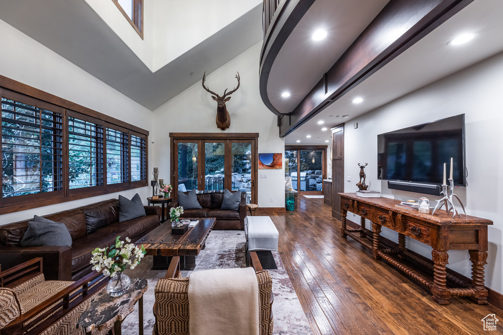 Living room with dark hardwood / wood-style flooring and high vaulted ceiling