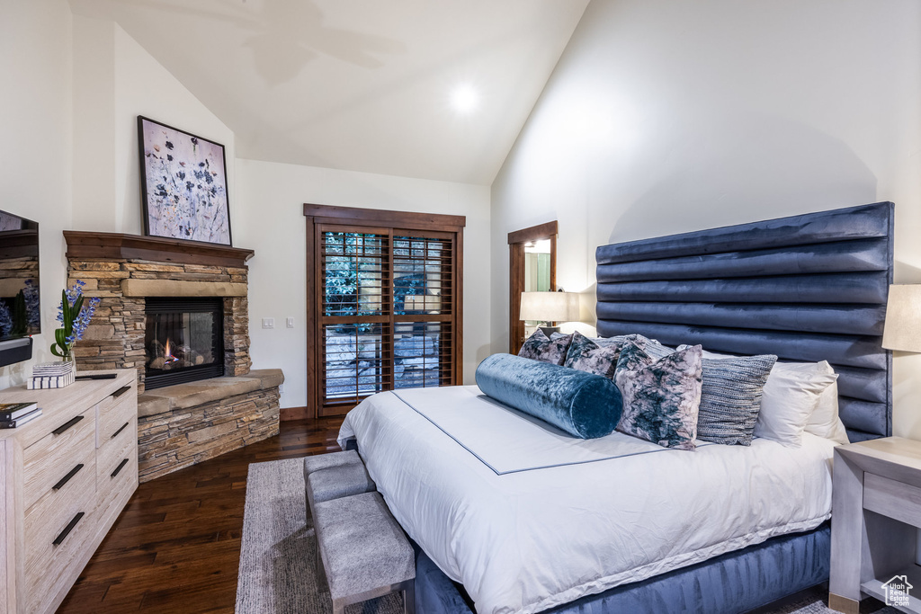 Bedroom with dark wood-type flooring, high vaulted ceiling, a fireplace, and ceiling fan