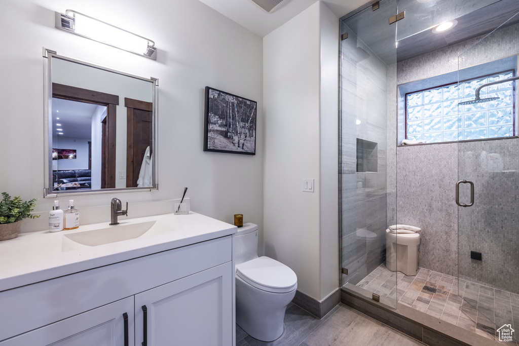 Bathroom with vanity, walk in shower, and toilet