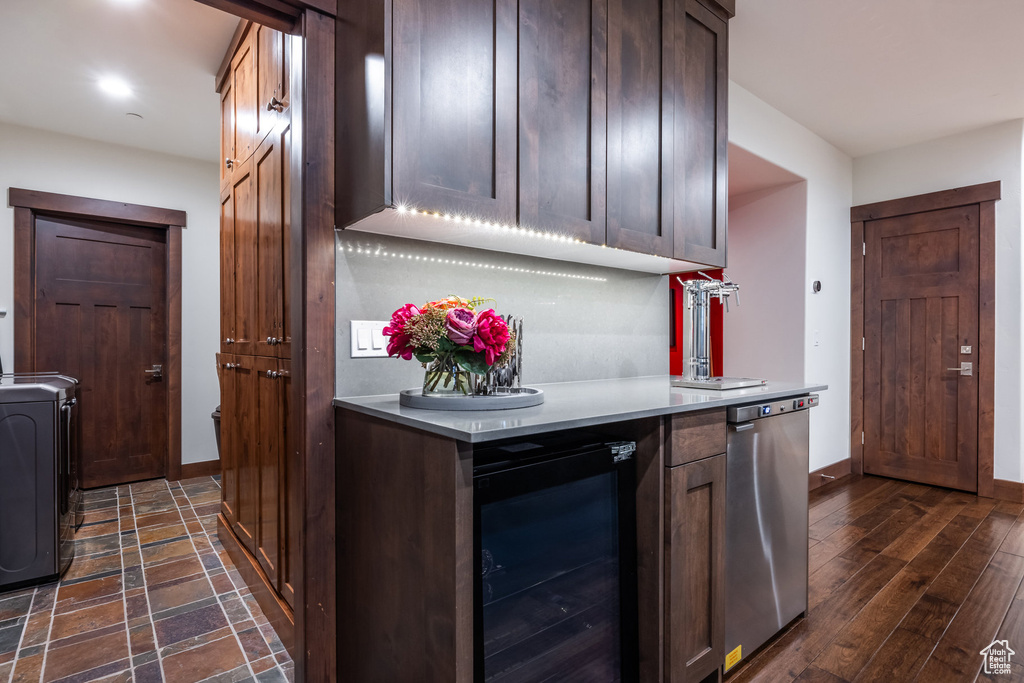 Kitchen with wine cooler, washer / clothes dryer, dark wood-type flooring, dishwasher, and dark brown cabinetry