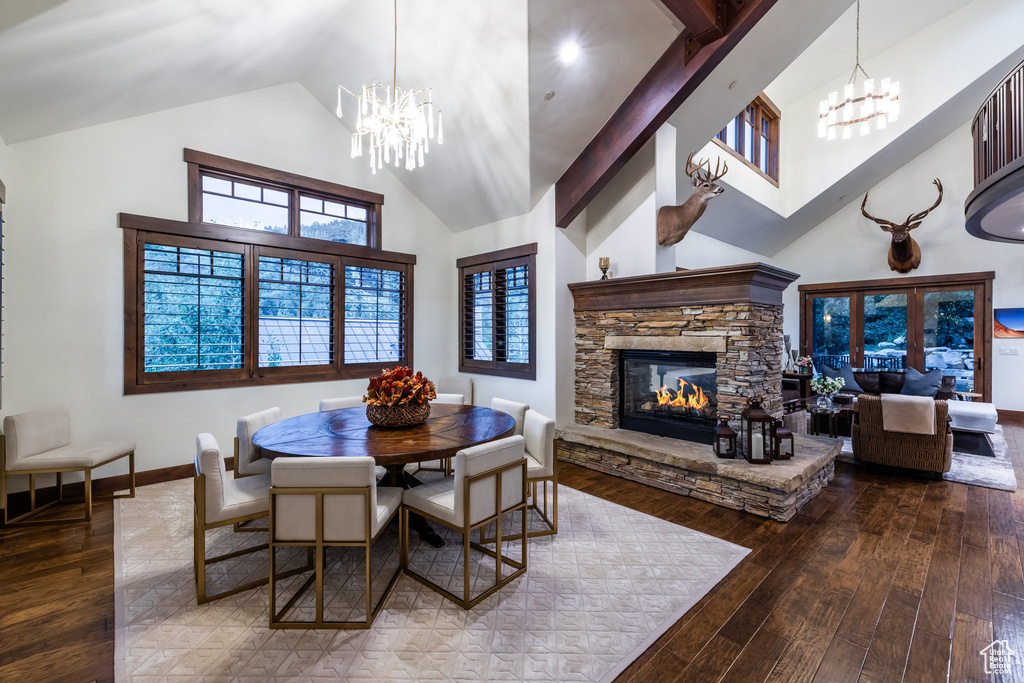 Dining space with beam ceiling, an inviting chandelier, a fireplace, hardwood / wood-style flooring, and high vaulted ceiling