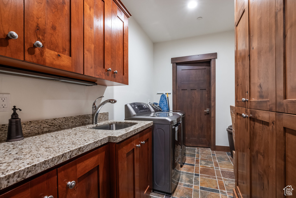 Washroom featuring sink, dark tile patterned flooring, cabinets, and independent washer and dryer