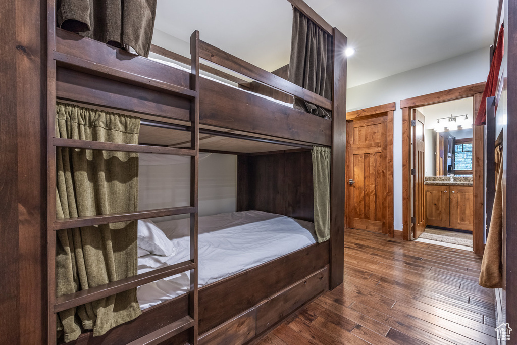 Bedroom with dark hardwood / wood-style flooring and connected bathroom