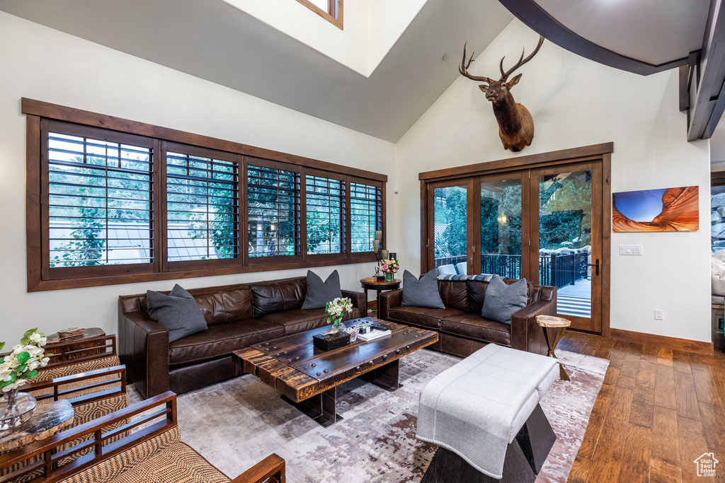 Living room with high vaulted ceiling, french doors, and wood-type flooring